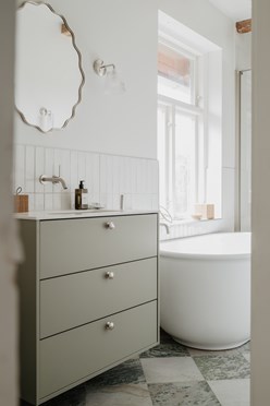 En grön kommod i lantlig stil med tvättställ och spegel